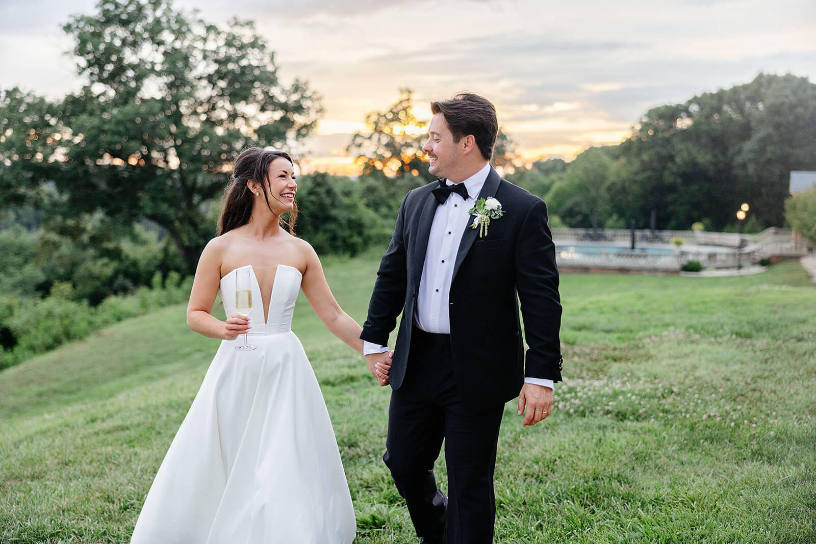 Estate at River Run Summer Wedding Photography 38 bride and groom holding hands and walking outside with the sun setting behind them