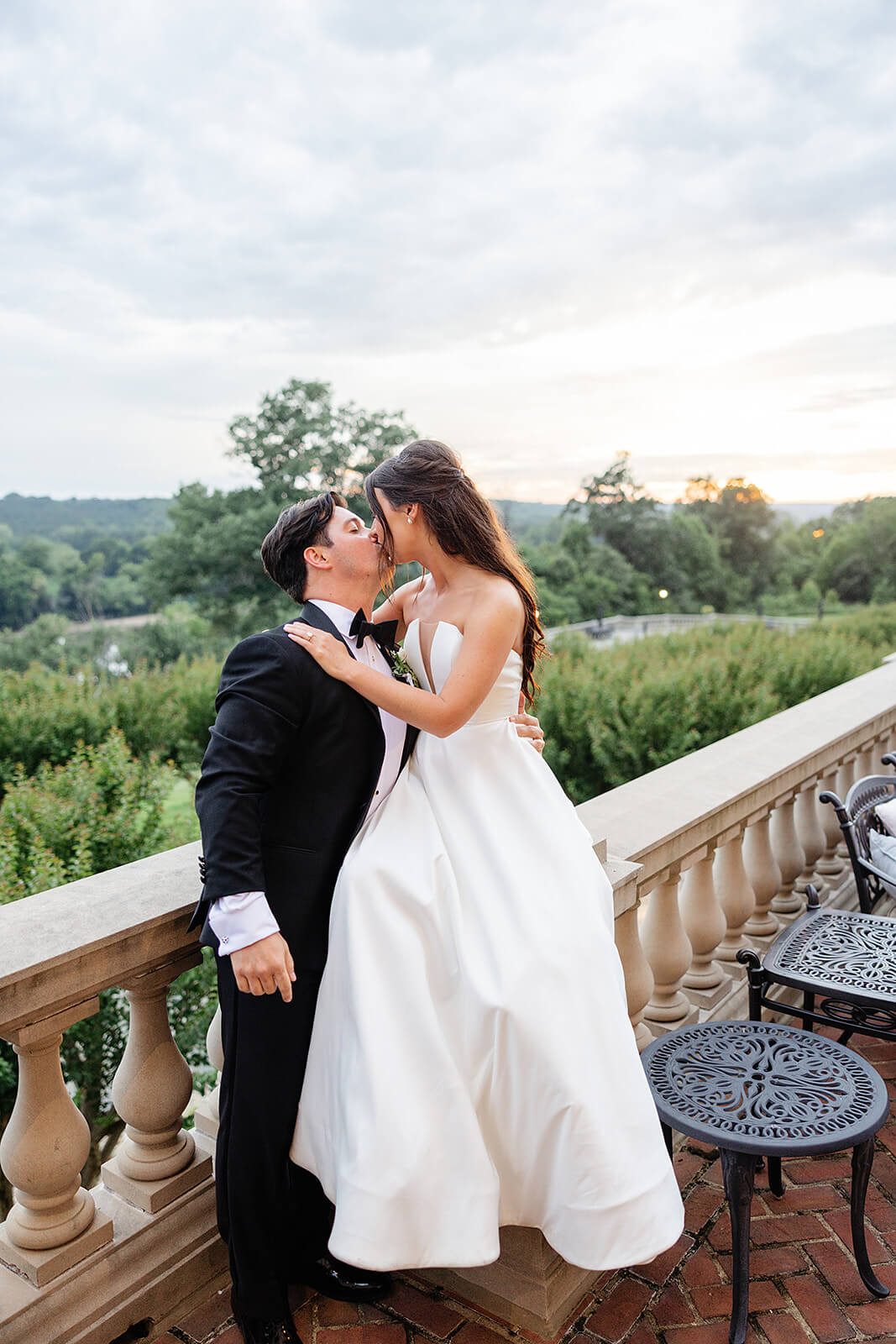 Estate at River Run Summer Wedding Photography 39 bride and groom kissing on brick balcony with the sun set behind them