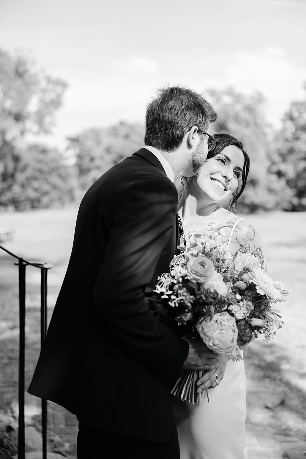 Laura Lee's Spring Wedding Photography 13 black and white photo of bride smiling as groom kisses her on the cheek