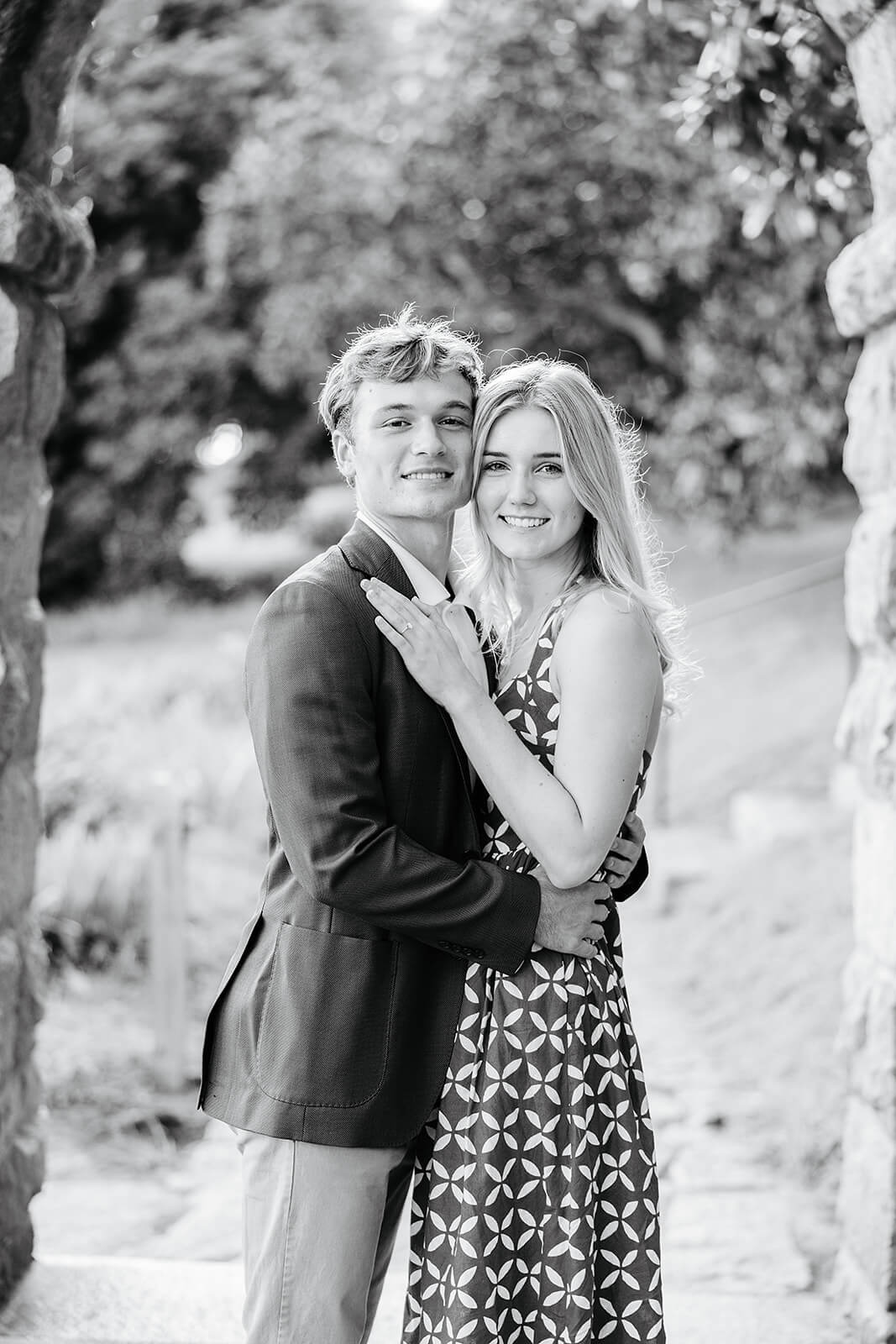 Maymont Summer Engagement Photography 7 black and white photo of couple hugging and facing camera while standing under a stone archway
