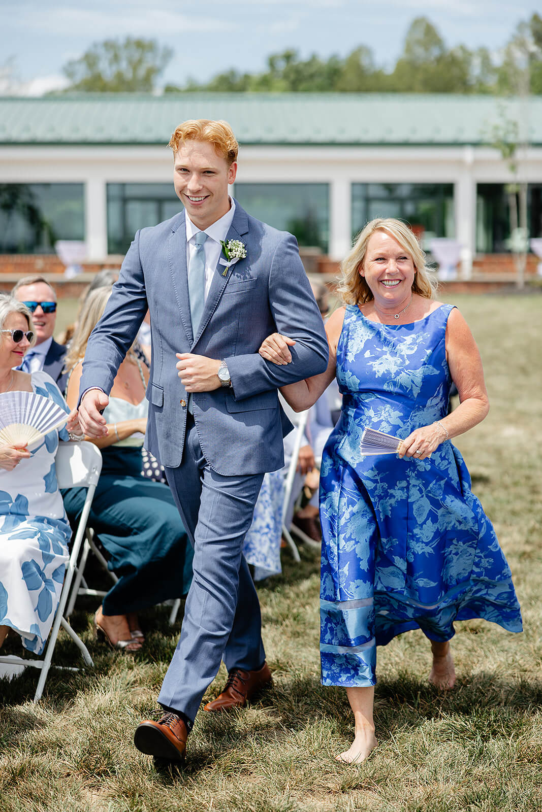 Rassawek Vineyard Spring Wedding Photography 13 mother of the bride walking down the aisle on the arm of a man in a blue suit