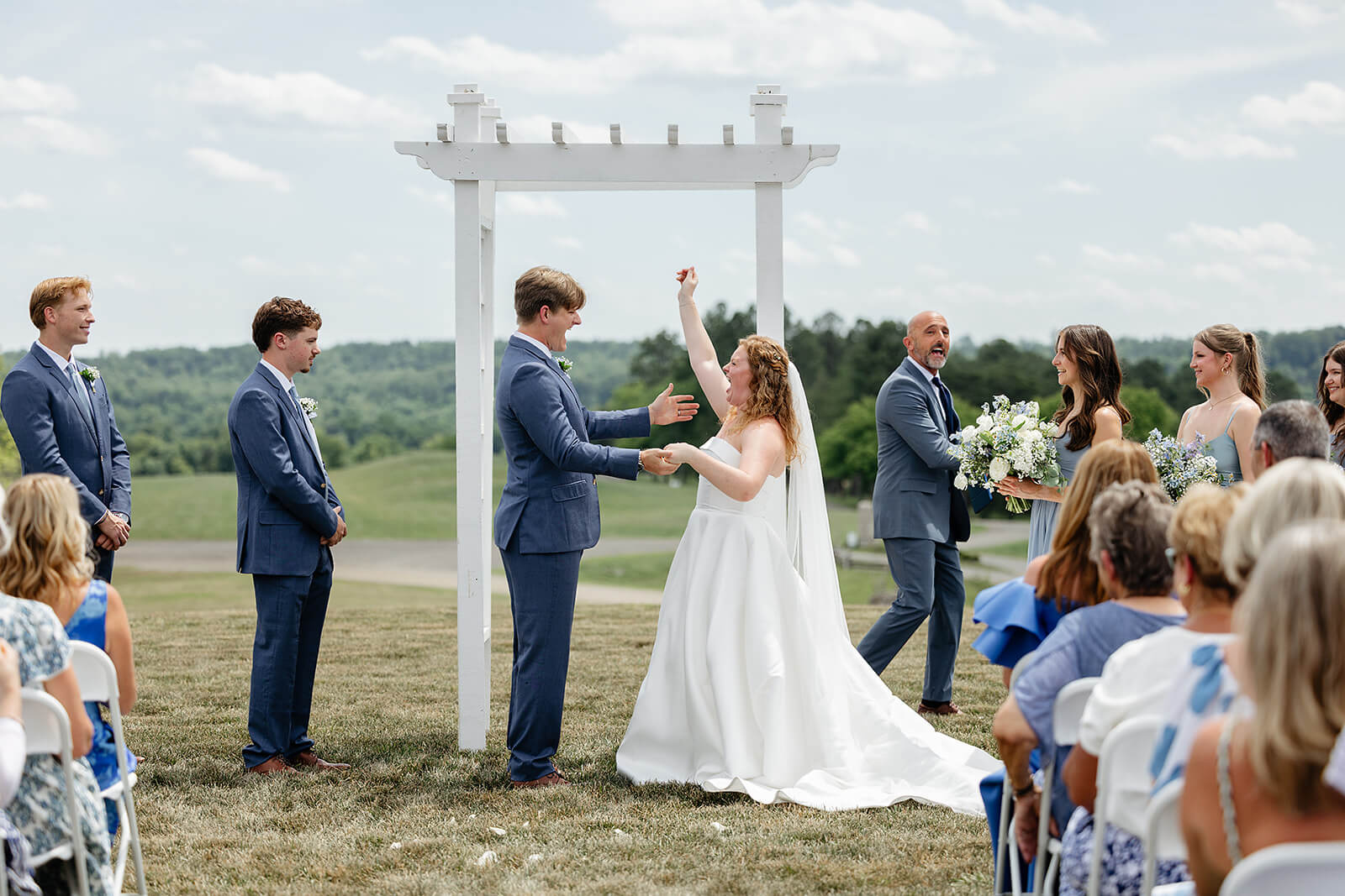 Rassawek Vineyard Spring Wedding Photography 16 bride cheering and holding her husbands hand as they stand at the alter