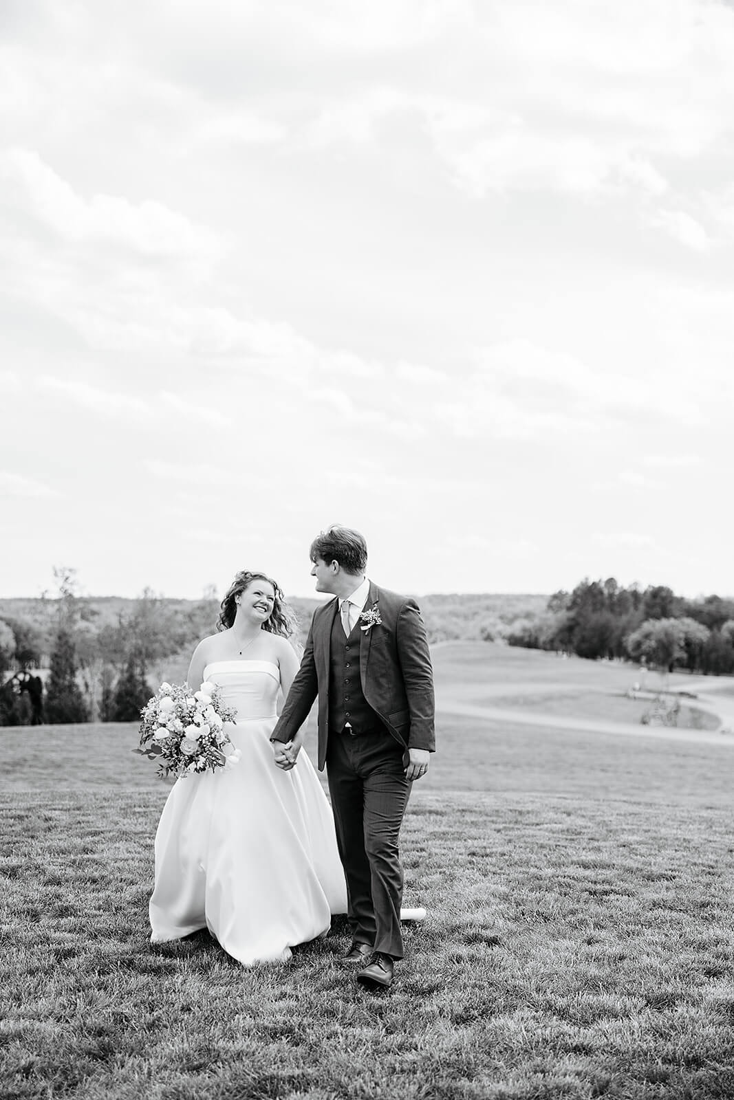 Rassawek Vineyard Spring Wedding Photography 22 black and white photo of bride and groom holding hands and walking across a sprawling lawn