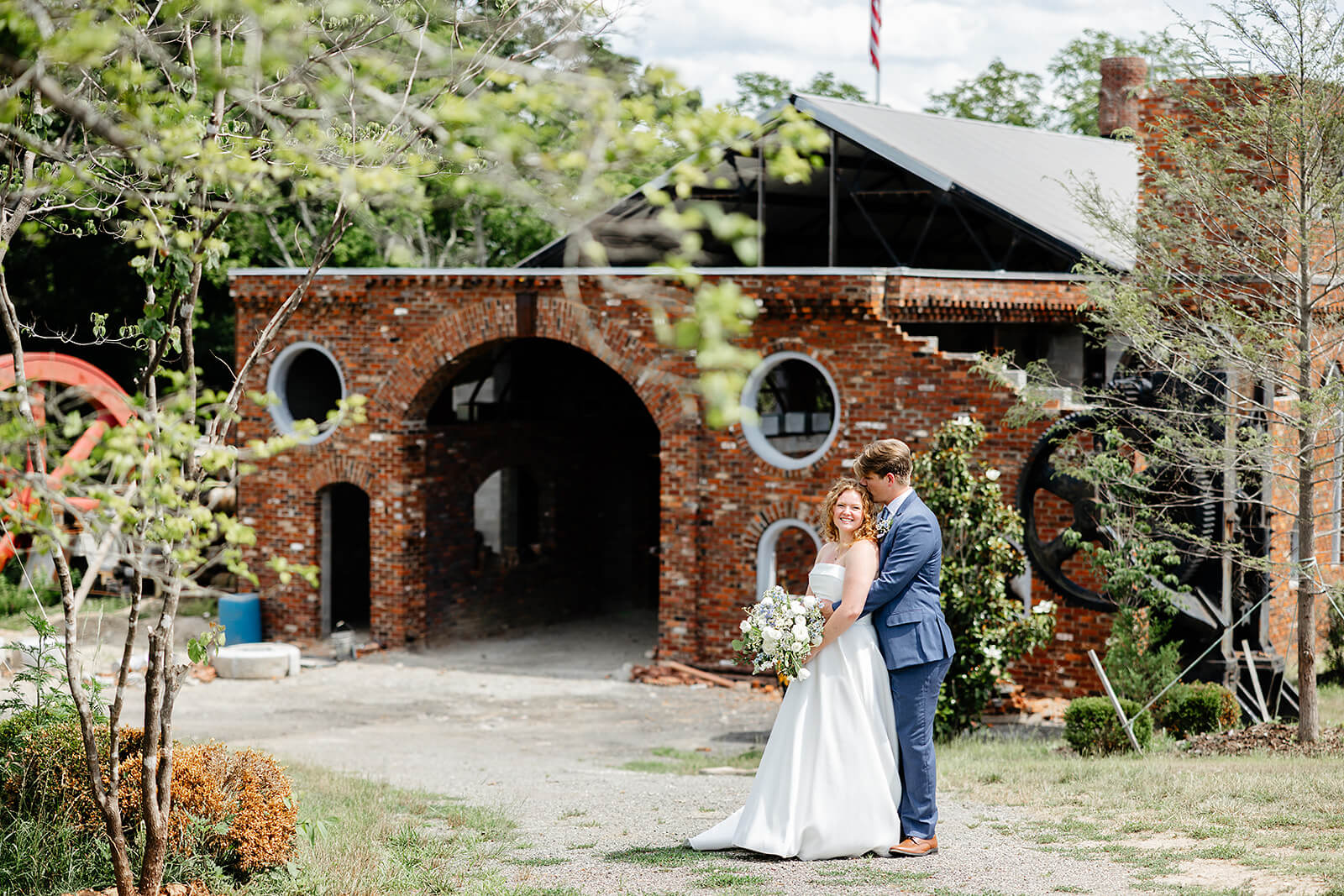 Rassawek Vineyard Spring Wedding Photography 23 groom hugging bride outside a brick building structure