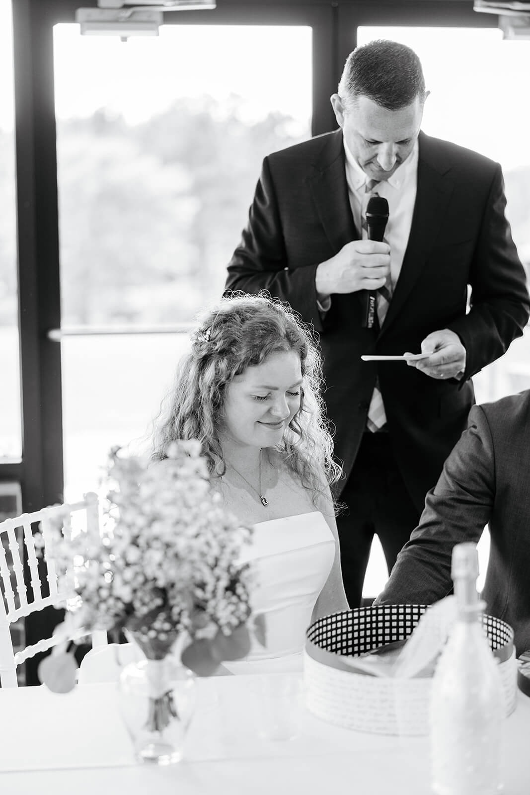 Rassawek Vineyard Spring Wedding Photography 36 black and white photo of bride smiling as a man prays over bride and groom