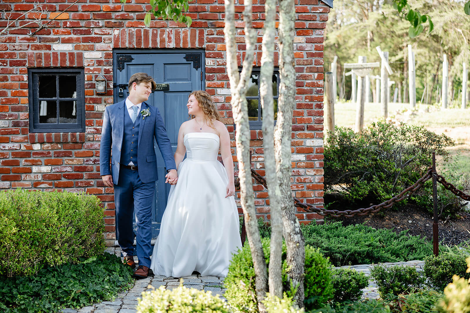 Rassawek Vineyard Spring Wedding Photography 30 bride and groom walking through greenery garden holding hands