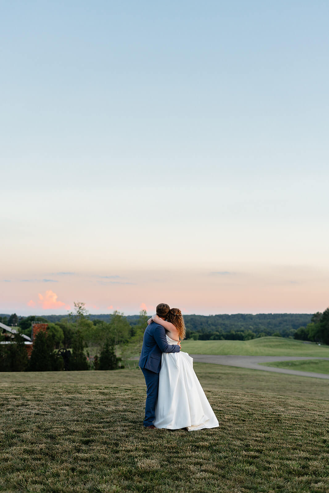 Rassawek Vineyard Spring Wedding Photography 50 bride and groom hugging on the lawn while watching the sun set