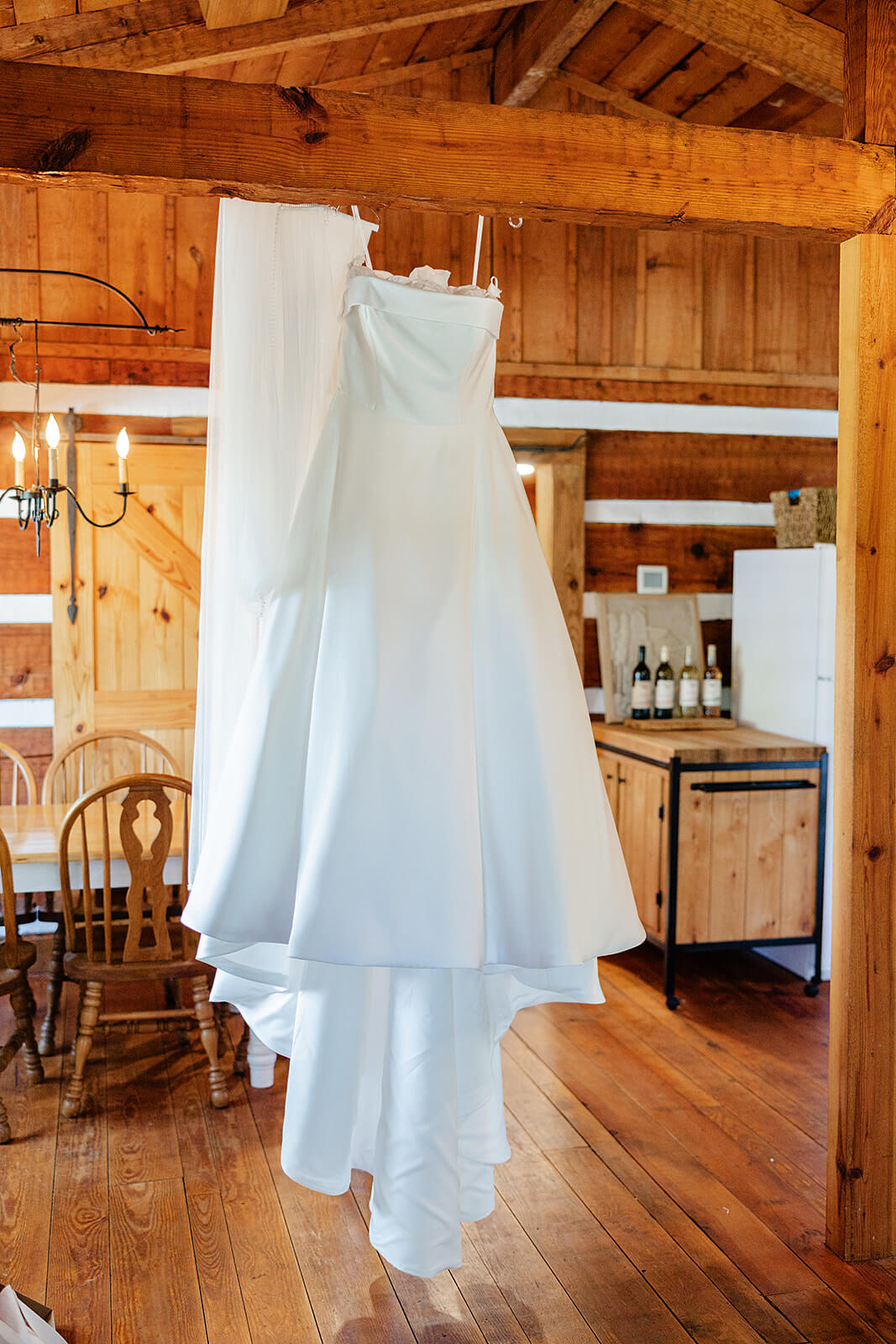 Rassawek Vineyard Spring Wedding Photography 4 bride's dress hanging from large wooden beam in wooden cabin style home