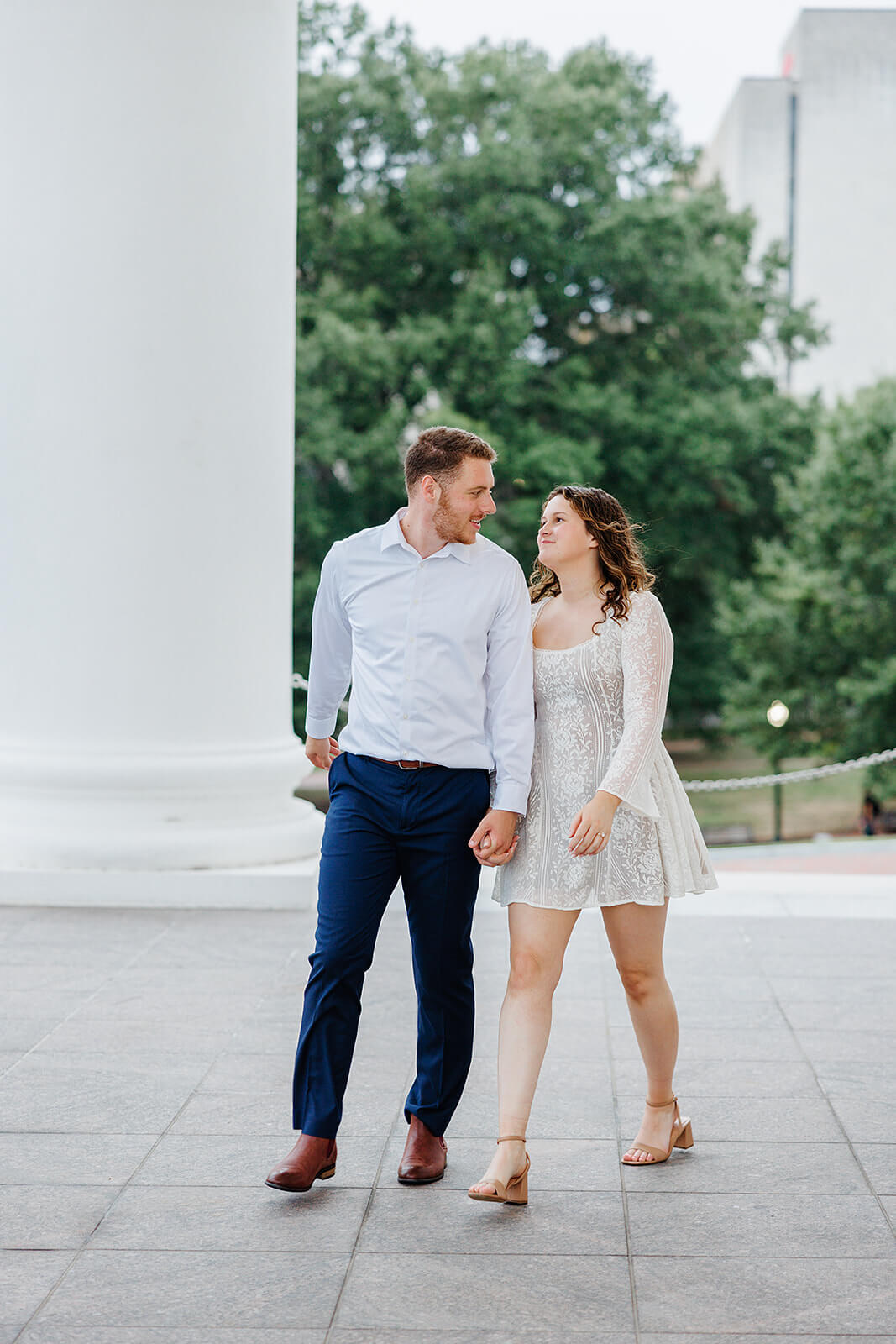 Virginia Capital Fall Engagement Photography 9 couple holding hands and walking across large stone porch with columns in the background