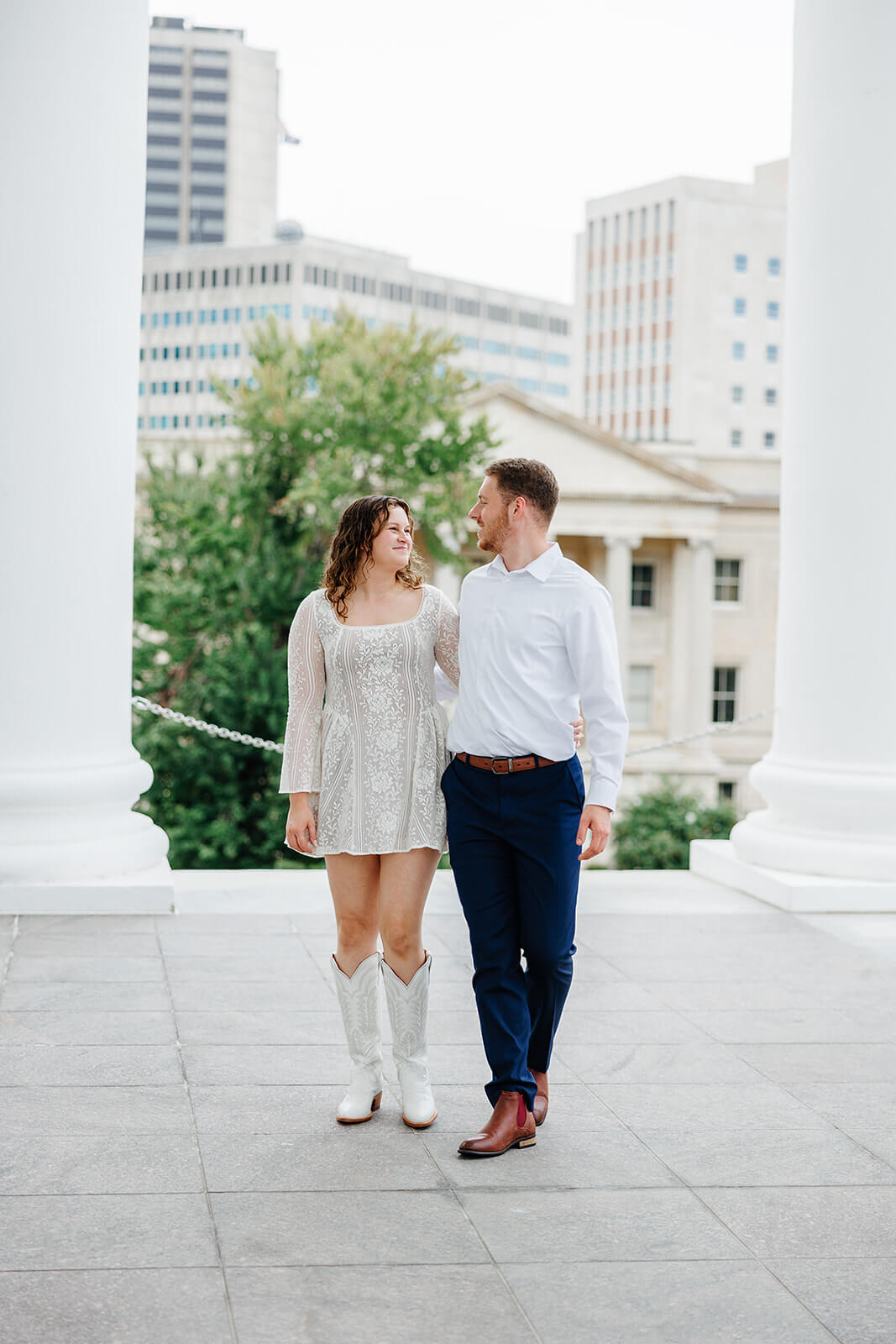 Virginia Capital Fall Engagement Photography 2 couple hugging each other from the side as they stand on large stone porch with white columns behind them